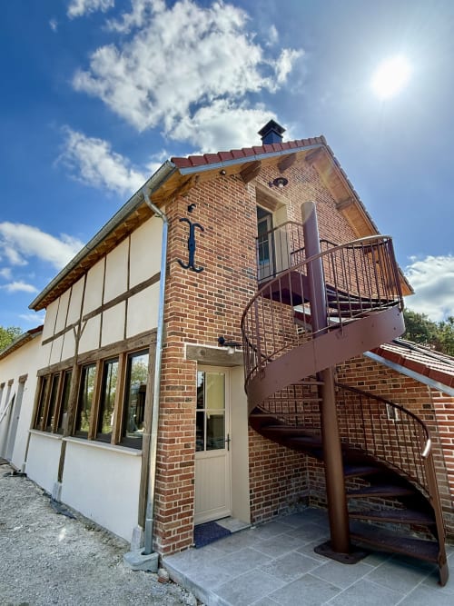 La Grange Aux Etangs B&B à Sennely : façade avec tour en brique, escalier en spirale et extensions modernes