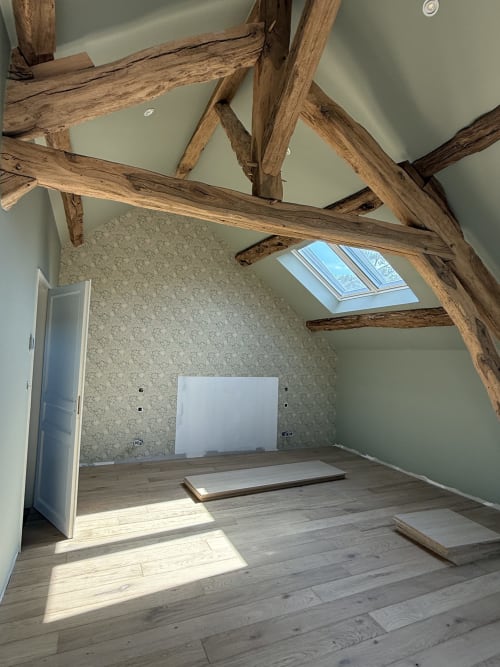 Chambre spacieuse sous les toits avec poutres apparentes, fenêtres de toit, parquet et papier peint à motifs à La Grange Aux Etangs