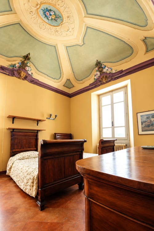Camera elegante al Bresbot B&B a Bressana con soffitto ornato, mobili in legno, pareti gialle e vista sul giardino