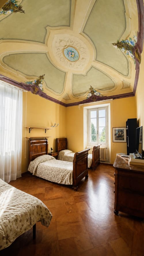Camera elegante al Bresbot B&B di Bressana con soffitto ornato, pareti gialle, letti in legno e vista sul giardino