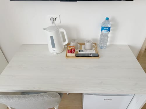 Scrivania della camera d'albergo con bollitore elettrico, bottiglia d'acqua e amenità di benvenuto presso Seveso Milan Central Rooms