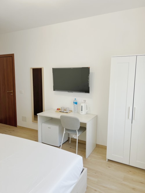 Camera moderna dell'hotel Seveso Milano con TV, scrivania di lavoro, frigobar e guardaroba a Milano