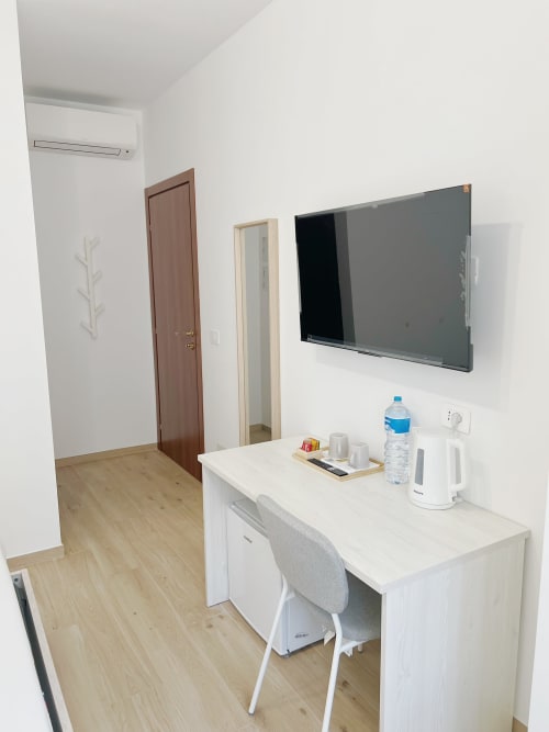 Camera moderna presso Seveso Milano Central con scrivania, TV a schermo piatto, pavimento in legno e climatizzatore