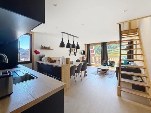 Modern open-plan duplex apartment with kitchen, dining area, and living room overlooking Montgenèvre ski slopes