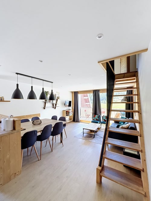 Modern open-plan dining area in L'AKWABA duplex at Les Tanières de Montgenèvre with wooden shelving, black pendant lights,