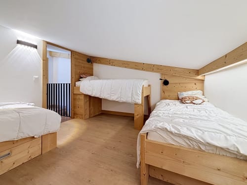Spacious duplex bedroom at Les Tanières with three wooden beds, pine walls, and mountain views in Montgenèvre