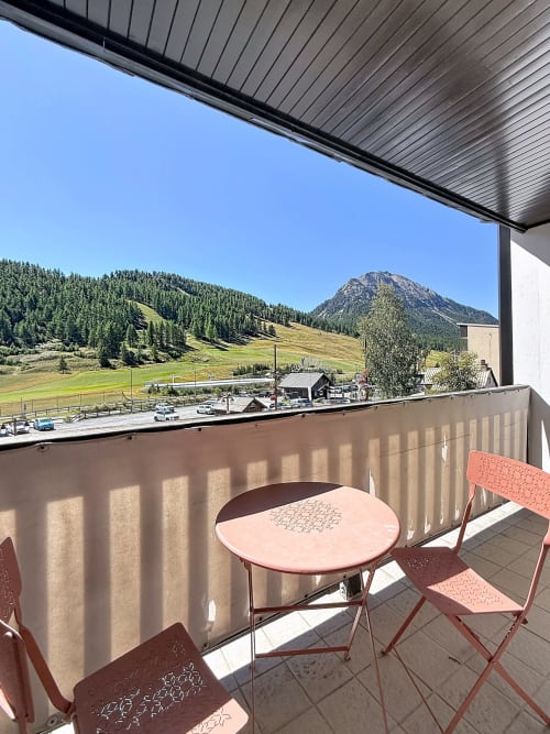 Balcony seating with mountain views at Les Tanières de Montgenèvre, overlooking alpine slopes and forested peaks
