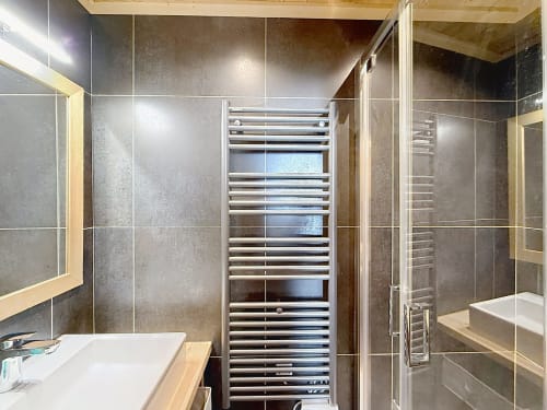 Modern bathroom in L'AKWABA duplex, Montgenèvre, with heated towel rail, large mirror, shower enclosure and tiled walls
