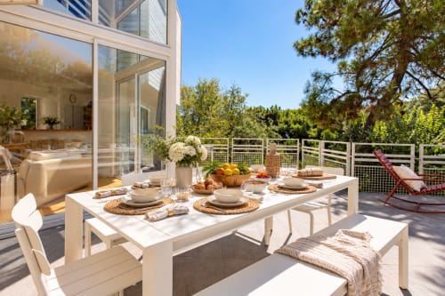Élégante terrasse de restaurant en plein air sur le pont ensoleillé de la villa La Loge Du Bassin, Lège Cap Ferret, avec vue sur l'océan et jardin