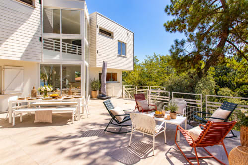 Terrasse ensoleillée de la Villa Cloudbreak à Lège Cap Ferret avec espace repas, chaises longues et vue sur le jardin près de l'océan