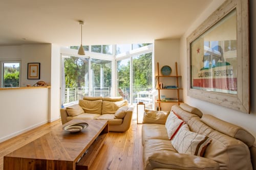 Salon lumineux avec sièges en cuir tanné, table en bois et grandes fenêtres donnant sur le jardin de Villa Cloudbreak