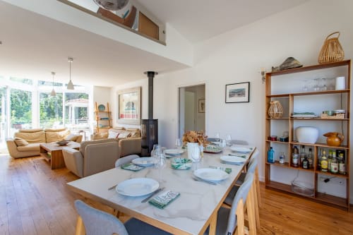 Espace ouvert de salle à manger et séjour à la Villa Cloudbreak avec table en marbre, sièges en cuir, étagères en bois et vue sur le jardin