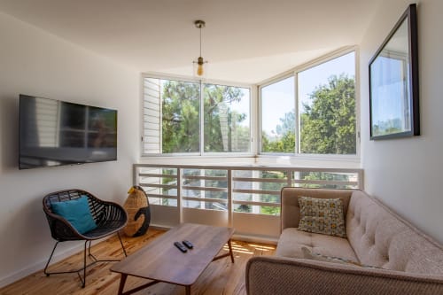 Salon moderne de villa avec vue sur jardin, sièges confortables, télévision et lumière naturelle par grandes fenêtres