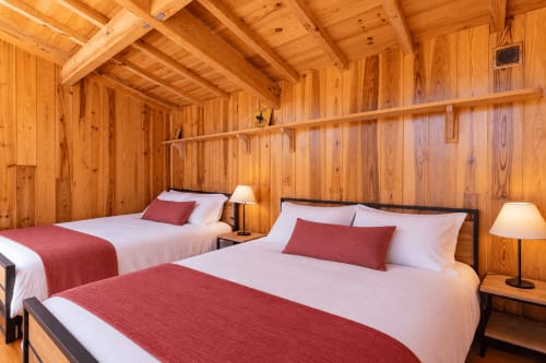 Chambre cosy de villa avec deux lits, touches rouges et poutres en bois rustique à Lège-Cap-Ferret