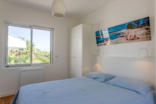 Chambre moderne lumineuse avec literie bleue à la Villa Cloudbreak à Lège-Cap-Ferret, vue sur jardin, luminaire suspendu