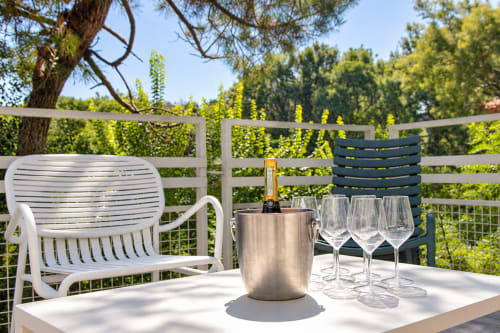 Terrasse extérieure de la Villa Cloudbreak avec seau à champagne, verres et transats blancs surplombant les jardins luxuriants près de Lège-Cap