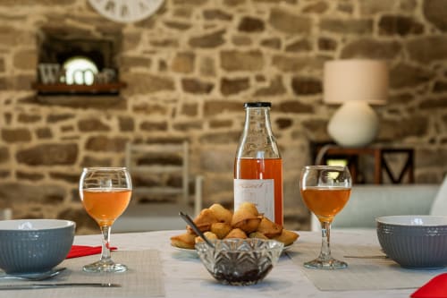 Table à manger du gîte Ferme de Kervihern avec vin, plateau de fromages et mur de pierre à Locoal-Mendon