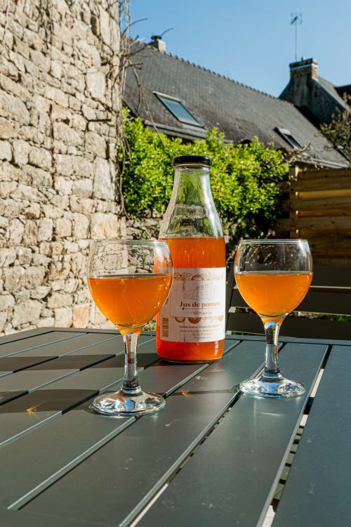 Deux verres de jus de pomme sur une table au gîte Ferme de Kervihern à Locoal-Mendon, avec murs en pierre et lierre