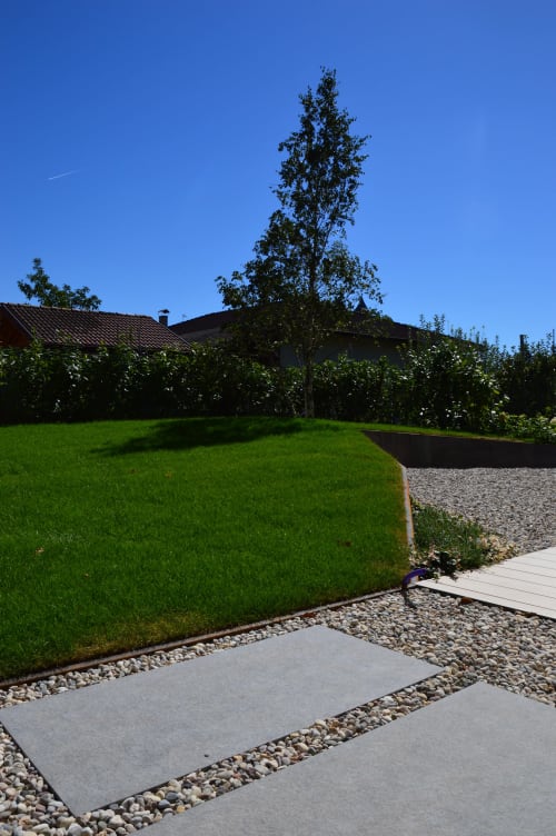 Prato rigoglioso e sentiero in pietra a Villa Rosati di Sanzeno, Trentino, sotto un cielo blu limpido