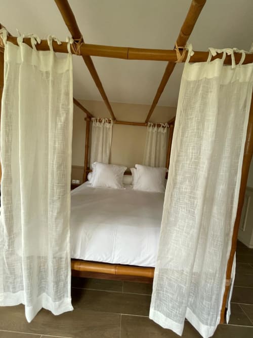 Lit à baldaquin en bois avec voilages blancs à Nomads Kodjoviakopé, un gîte à Lomé, Togo