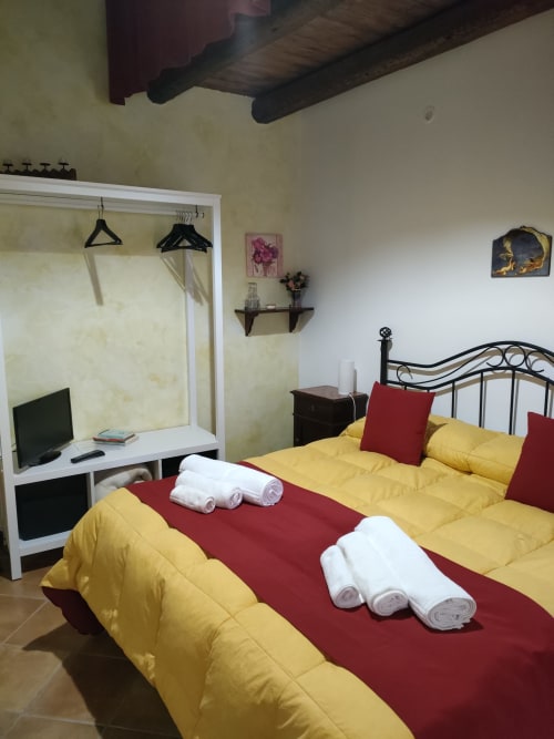 Camera luminosa nell'Appartamento Bordeaux a Case Vacanze Borgo i Stritti con due letti singoli, biancheria gialla, accenti rossi e scrivania