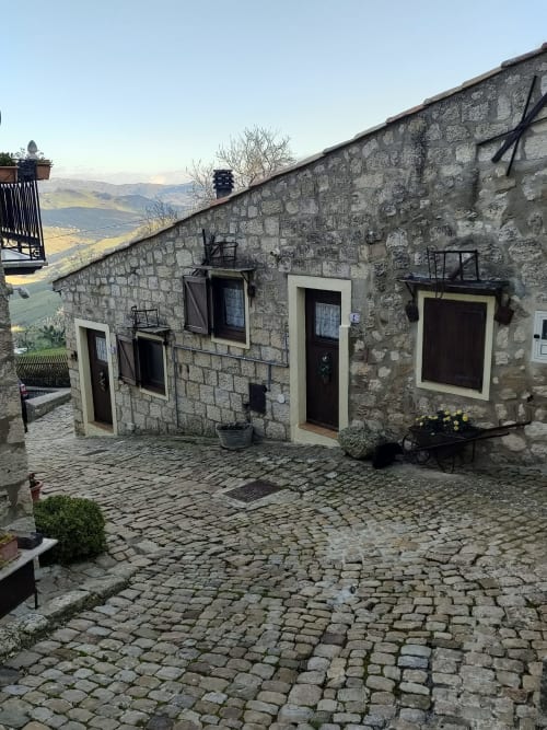 Edificio in pietra a Case Vacanze Borgo i Stritti a Petralia Soprana con viste montane, cortili e fiori