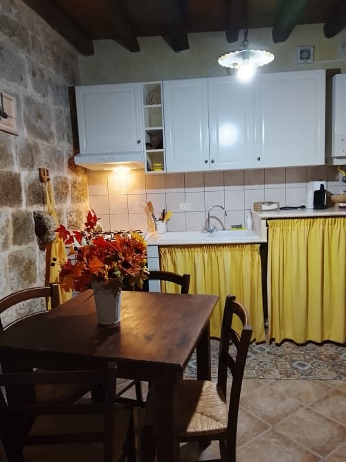Luminosa zona cucina-pranzo in Appartamento Giallo a Case Vacanze Borgo i Stritti, Petralia Soprana, con tavolo in legno, rosso