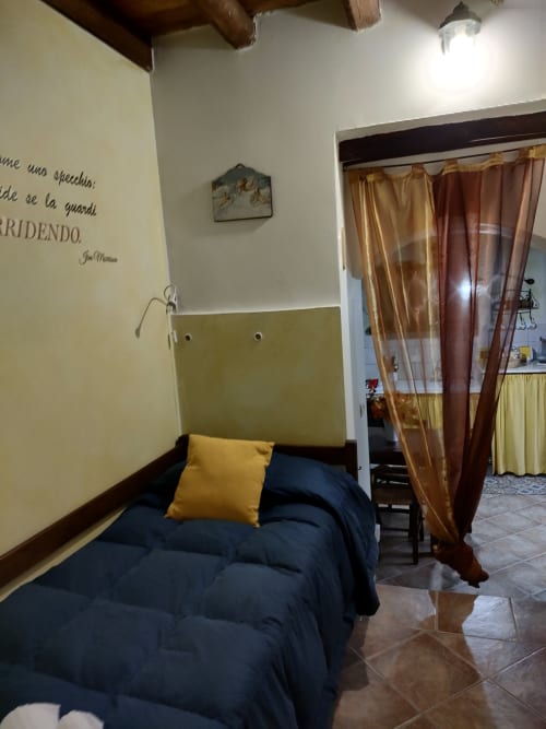 Camera accogliente a Case Vacanze Borgo i Stritti con bedding blu, testata gialla e tende con vista montagna a Petralia
