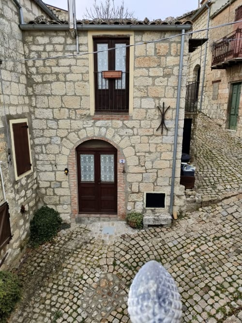 Corte medievale in pietra a Case Vacanze Borgo i Stritti, Petralia Soprana, con portale ad arco e sentieri lastricati