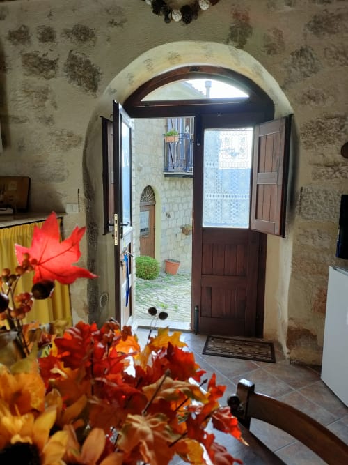 Arco in pietra con fiori rossi al Case Vacanze Borgo i Stritti di Petralia Soprana, vista della corte