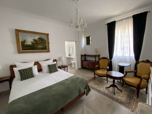 Elegant bedroom at Domaine de Bize Mirepoix with queen bed, crystal chandelier, and period furnishings in Ariège