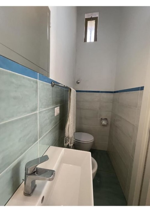 Bagno moderno con lavabo bianco, piastrelle, dettagli blu, wc e zona doccia nell'appartamento Casa Ida, Vietri sul Mare