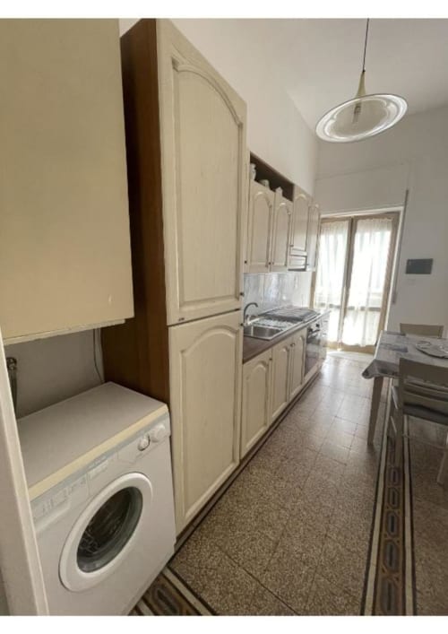 Cucina moderna nell'appartamento Casa Ida a Vietri sul Mare con mobili color crema, piano cottura, lavatrice e pavimentazione in piastrelle
