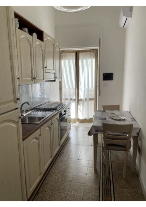 Cucina moderna con mobili color panna, elettrodomestici in acciaio inossidabile, tavolo da pranzo e porte-finestre in vetro nella Casa Ida 2