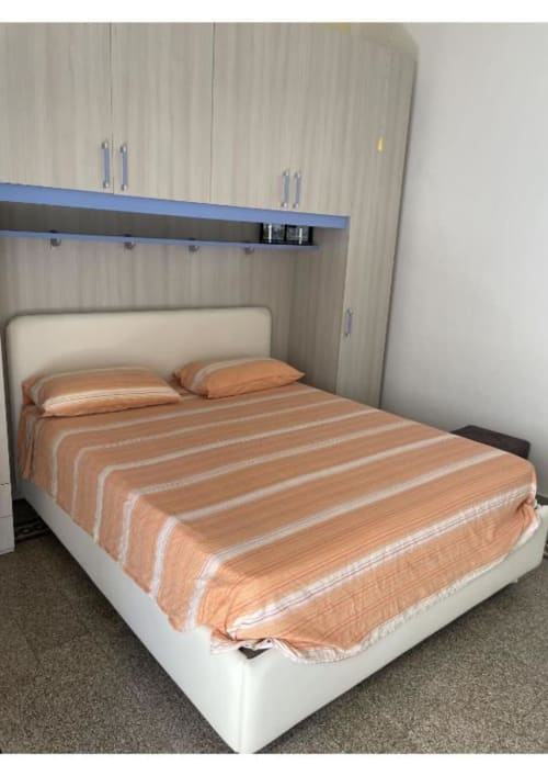 Camera da letto moderna presso Casa Ida a Vietri sul Mare con letto color crema, biancheria a righe arancioni e armadi in legno integrati