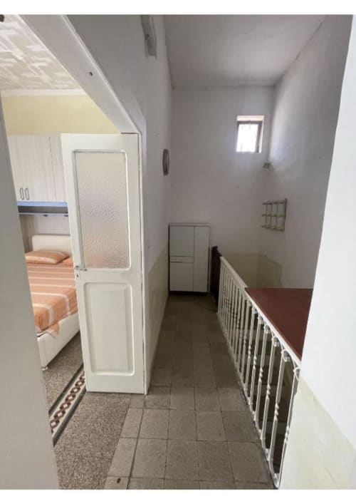 Stretto corridoio dell'appartamento Casa Ida 2, Vietri sul Mare, con porta bianca, ringhiera e vista sulla camera da letto