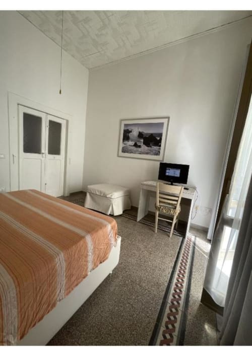 Camera da letto dell'appartamento Casa Ida 2 a Vietri sul Mare con letto, TV, scrivania e quadri su pareti bianche