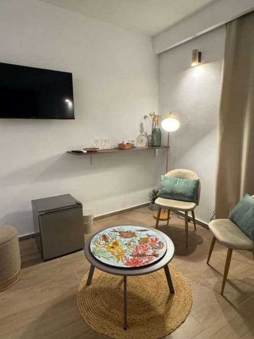 Accogliente soggiorno di Casa Ida BnB a Vietri con tavolo floreale tondo, comode sedute e TV a parete