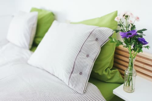 Chambre accueillante au B&B Place Jourdan Bruxelles avec literie verte, oreillers rayés et fleurs fraîches en vase