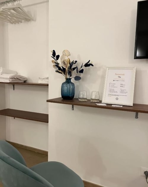 Mensola della camera ospiti Casa Ida Vietri con vaso blu, fiori secchi, bicchieri e cartello di benvenuto
