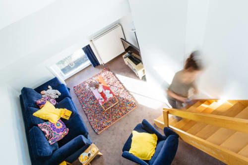 Vue de dessus de la chambre d'hôte accueillante de Place Jourdan Bruxelles avec fauteuils bleus, tapis coloré et escalier en bois