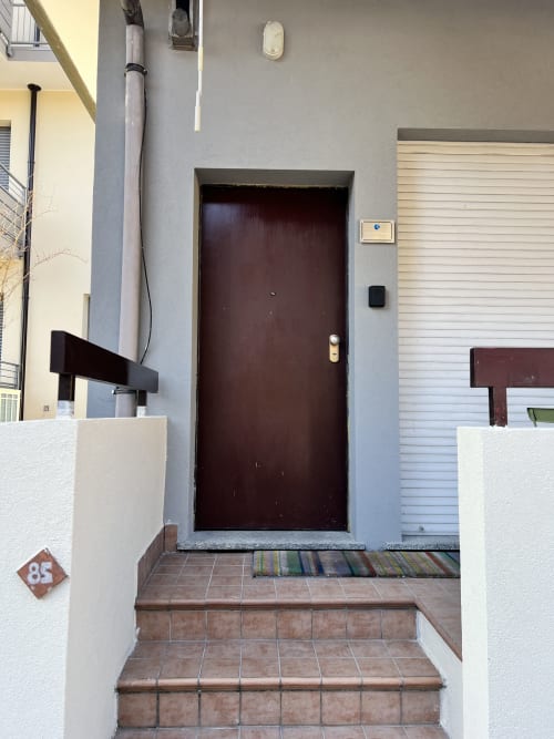 Ingresso privato all'appartamento di Le case di Angy ad Albese Con Cassano, Italia, con porta bordeaux e percorso piastrellato