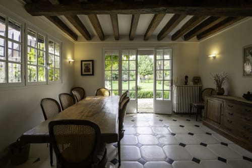 Élégante salle à manger avec poutres apparentes, vue sur le jardin par portes-fenêtres et carrelage motifs à Domaine