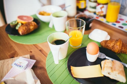 Petit-déjeuner copieux à la Chambres d'hôtes Place Jourdan Bruxelles : café, jus d'orange, croissants, œufs, fromage et pâtisseries sur bois