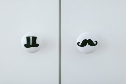 Deux boutons de tiroir blancs ornés d'un haut-de-forme noir et d'une moustache à B&B Place Jourdan, Bruxelles