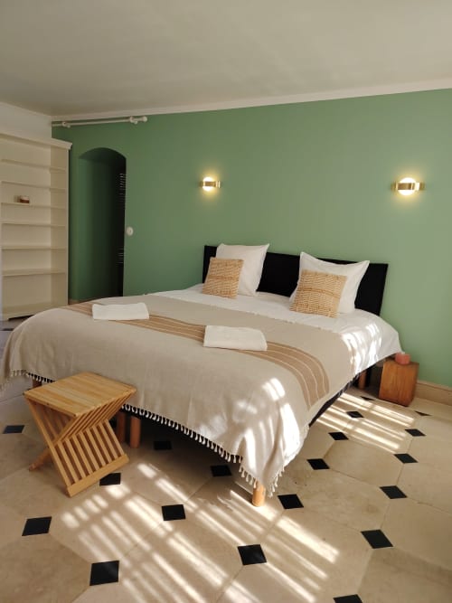 Chambre lumineuse aux murs vert sauge, lit queen avec draps blancs, touches de bois et vue sur le jardin au Domaine Chapelle