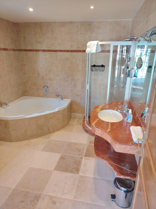 Salle de bain luxueuse du Domaine Chapelle avec baignoire d'angle, douche à l'italienne et vasque en marbre rouge à La Chapelle-la-Reine