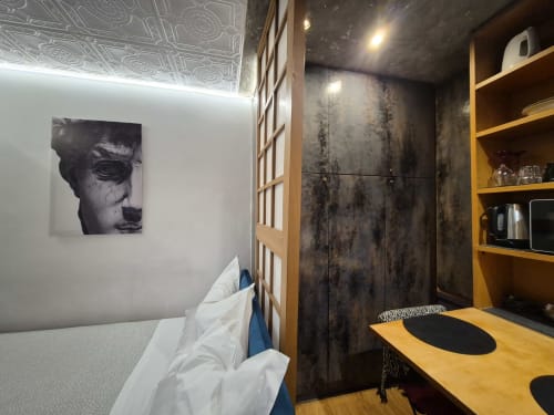 Camera moderna a Babaja Roma con letto, scrivania con mensole gialle, elementi decorativi nero e oro, design contemporaneo