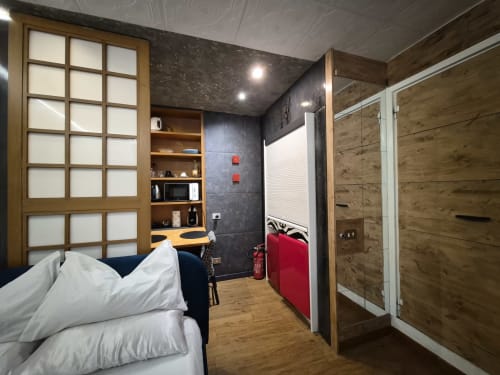 Camera da letto moderna dell'appartamento Giulia's Nidus a Roma con arredamento in legno, biancheria bianca, doccia in vetro e vista sulla città