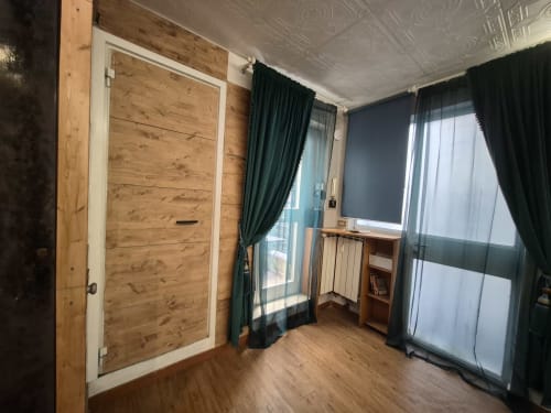 Appartamento Nidus di Giulia a Roma con porta in legno, tende verdi e vista sulla città dal balcone